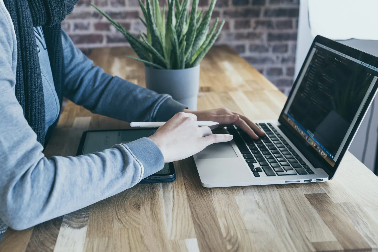 Manos programando en un portátil sobre una mesa de madera