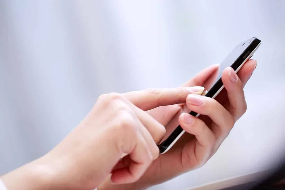 Mano sosteniendo un móvil con la app de cita previa de CIGES