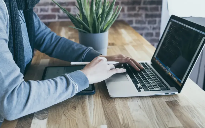 Manos programando en un portátil sobre una mesa de madera