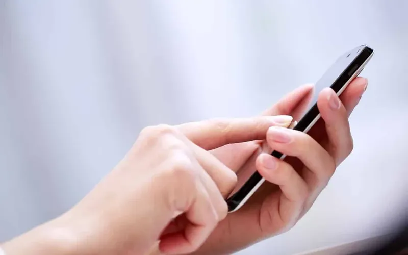 Mano usando la app de cita previa de CIGES en el móvil