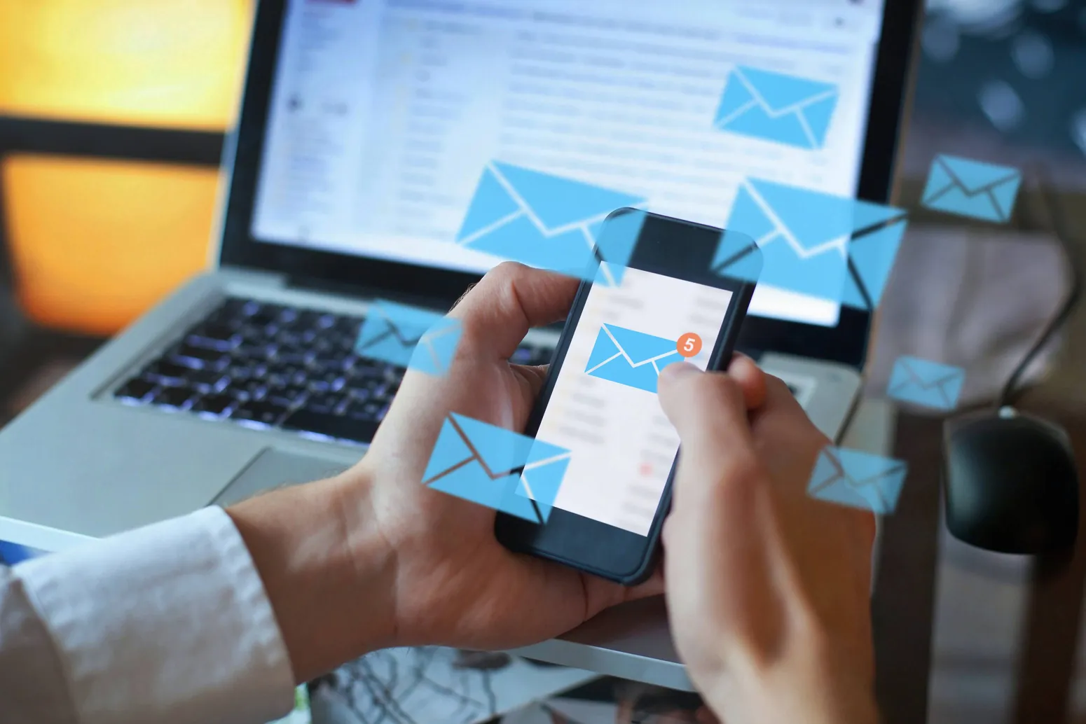 Manos con un teléfono móvil del que salen avisos por correo electrónico