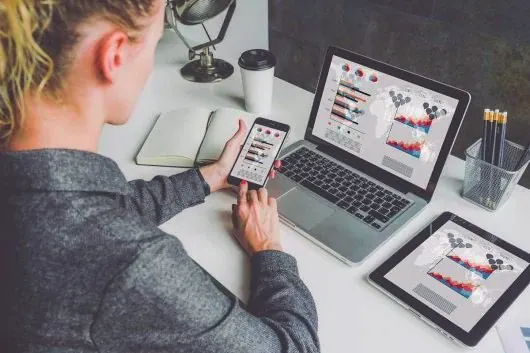 Usuaria con móvil, portátil y tableta consultando gráficas