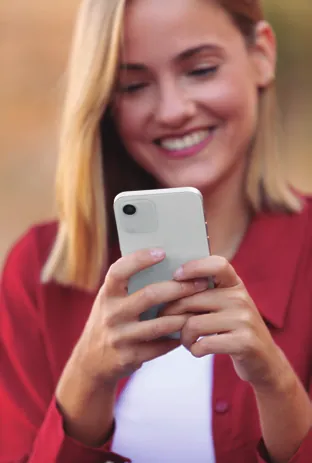 Mujer sonriente consultando su cita en el teléfono móvil